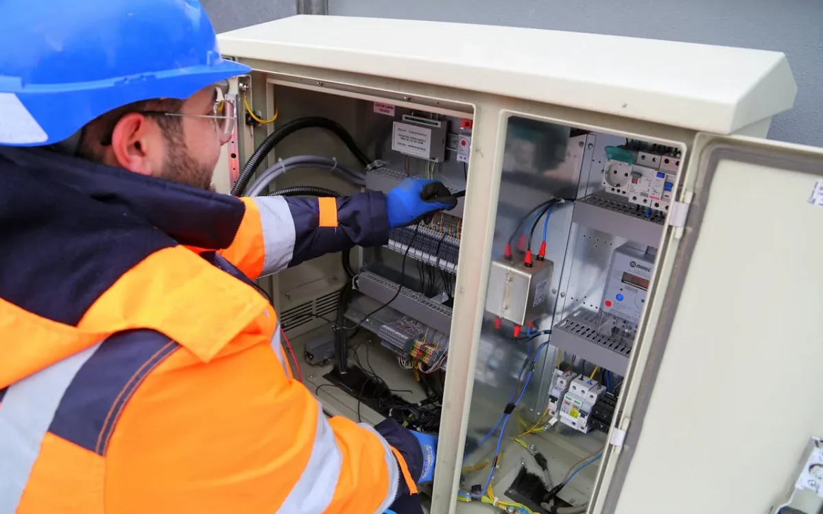 DrBuild technicians installing circuit breakers in an open electrical panel during a construction project