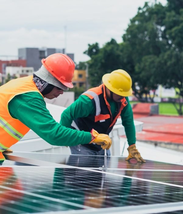 Technicians installing commercial solar panels with battery storage on an industrial site